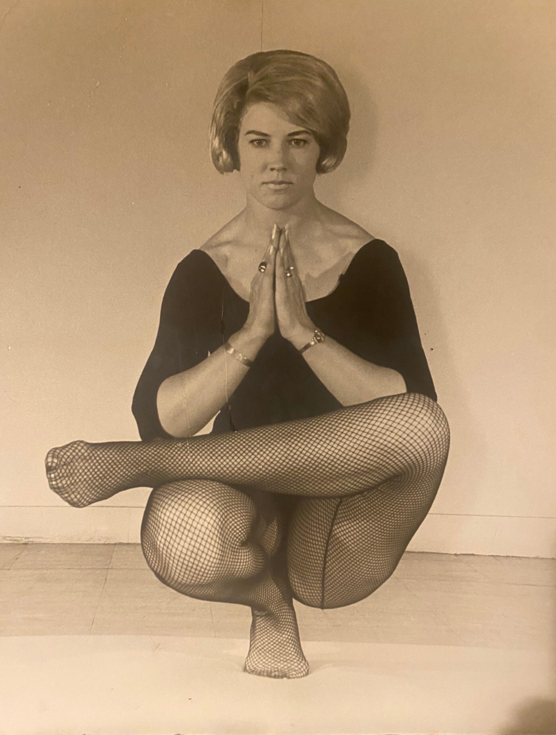 Ailsa Gartenstein in a seated balance with hands joined at the chest, sepia studio portrait